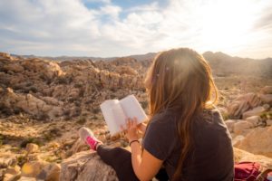 woman reading on top of a mountain